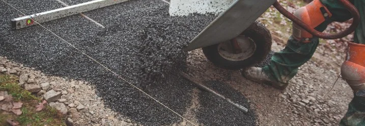 Person schüttet Kies aus Schubkarre